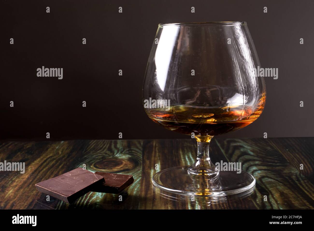 Glass with cognac and dark chocolate. Dear elite alcohol on a dark brown background. Alcoholic drinks. Stock Photo