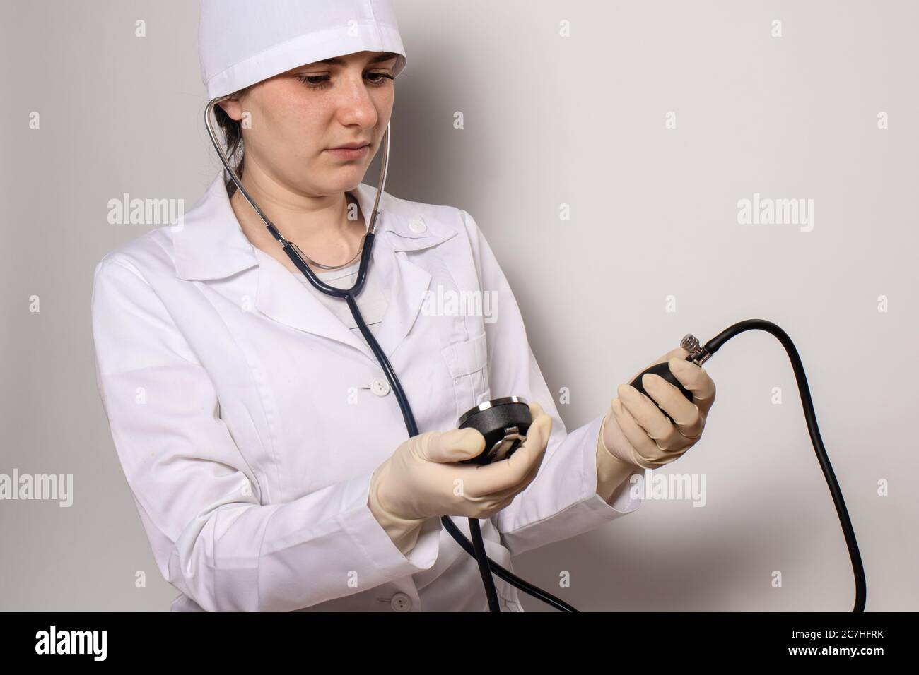 A doctor in a medical cap and uniform, a cardiologist measures blood