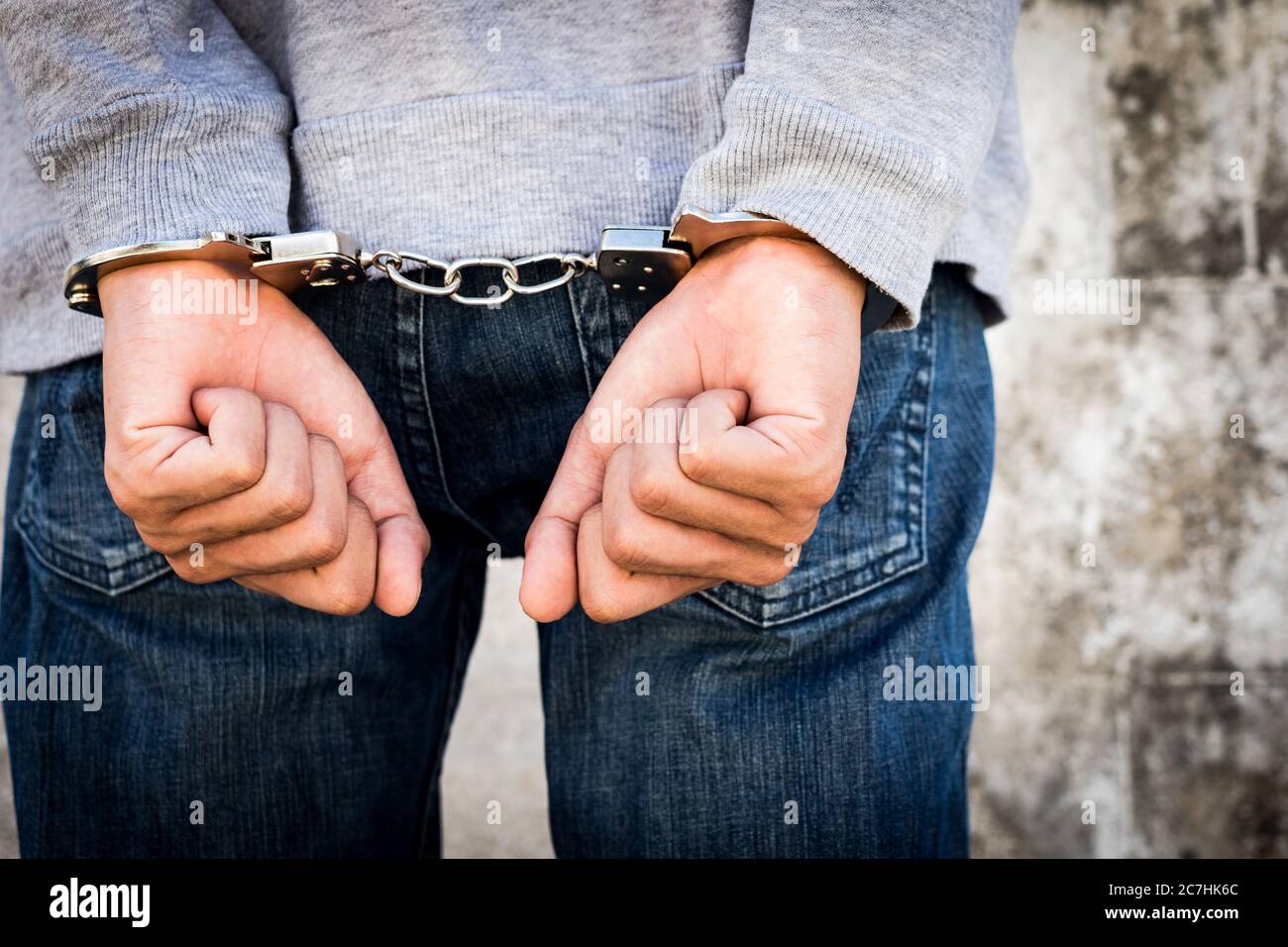 Close up hands tied up handcuffs in behind his body. Arrested man