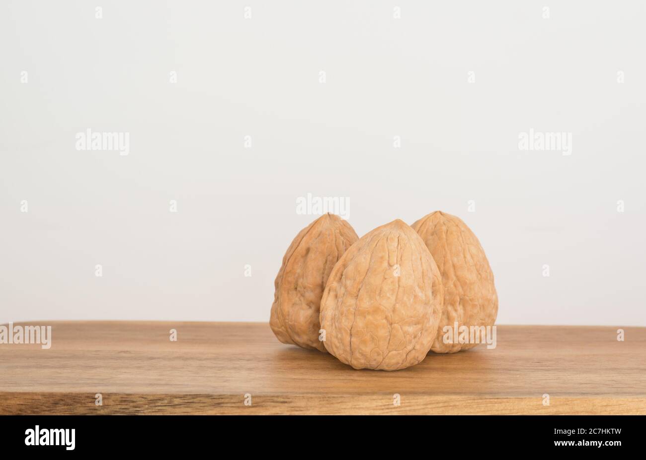 Three whole walnuts on a wooden board Stock Photo