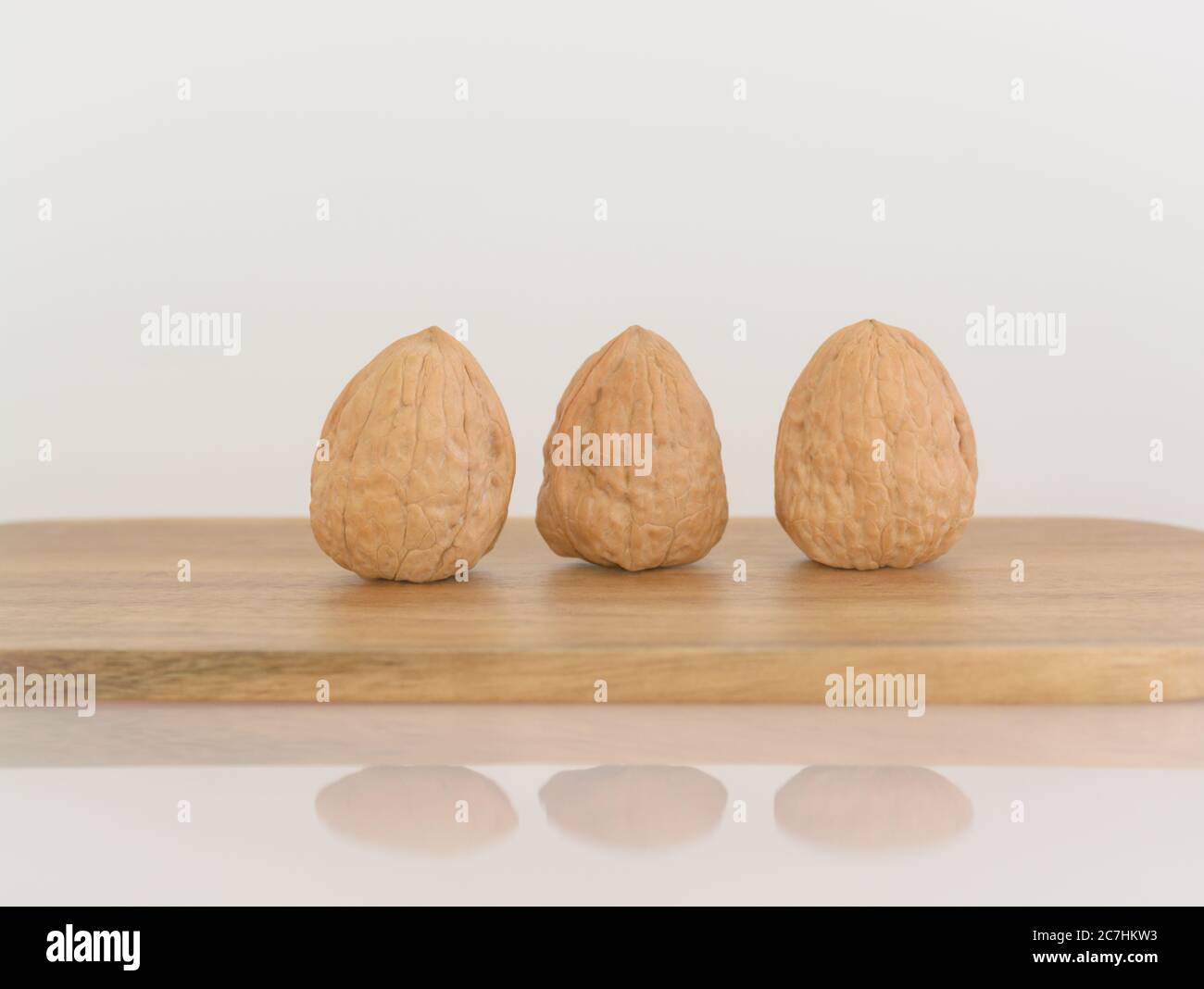 Three walnuts on a wooden cutting board Stock Photo