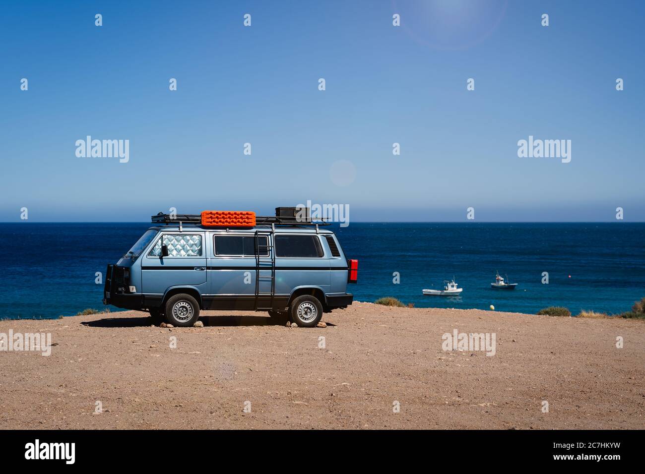 Camper van parked on the beach in front of the blue sea during holidays ...
