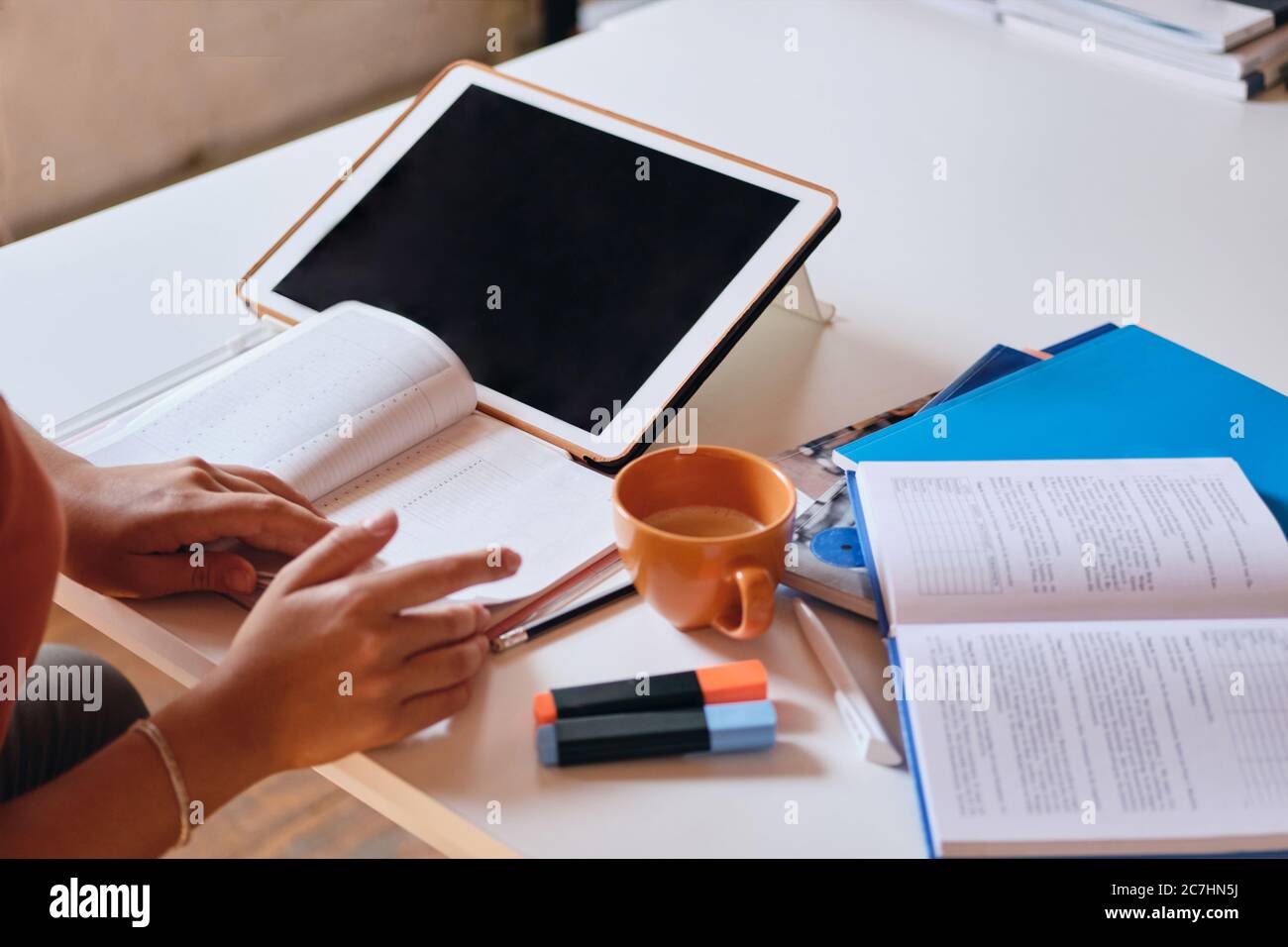 Close up photo of girl studying with tablet,textbooks and cup of coffee on desk at home Stock Photo