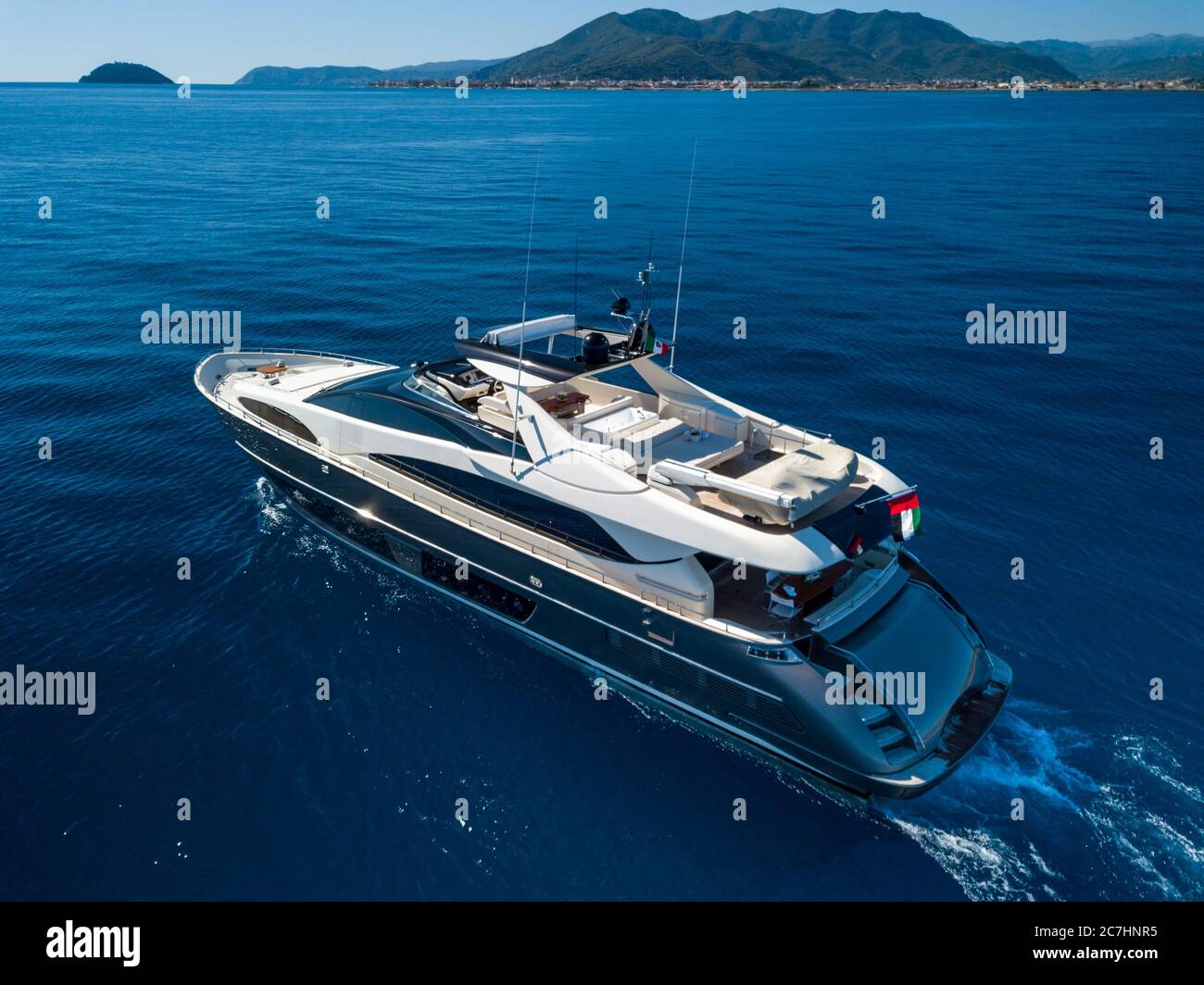 High angle shot of a yacht sailing on the sea with mountains in the ...