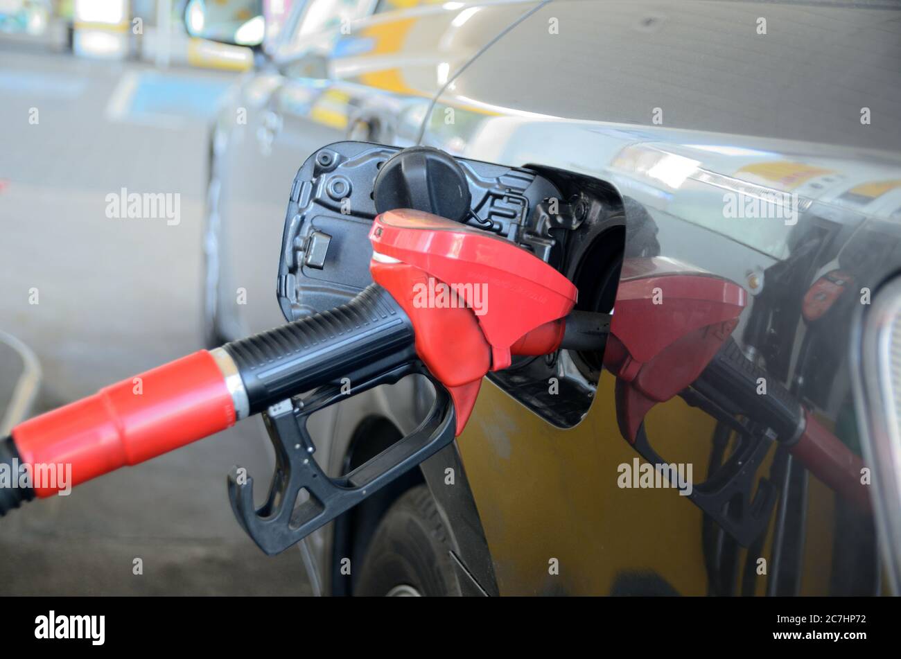 Charging petrol at petrol station. Car with open fuel filler cap parked at petrol station Stock