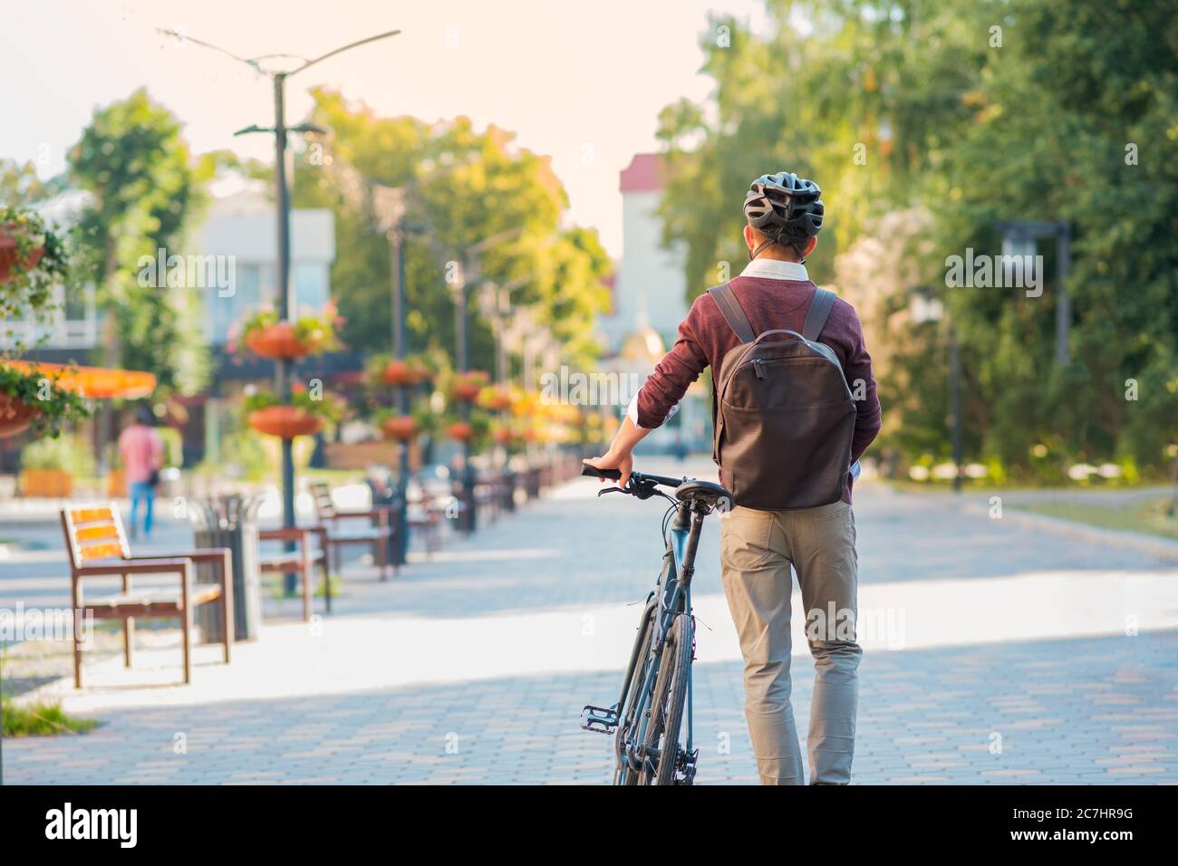 Male commuter wearing bike helmet walking away. Safe cycling in city