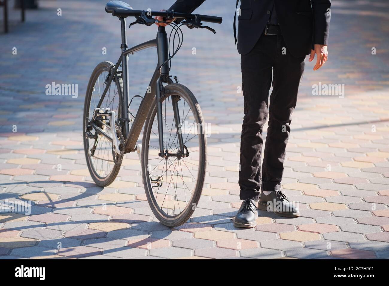 Male person in a suit holding a commuter bike. Cycling around the city