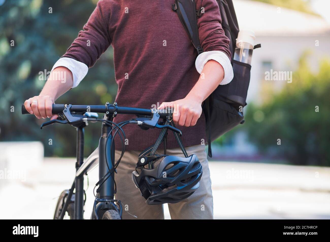 Commuter bike in hands of a male millennial, urban background. Safe cycling in the city, active urban lifestyle concept Stock Photo