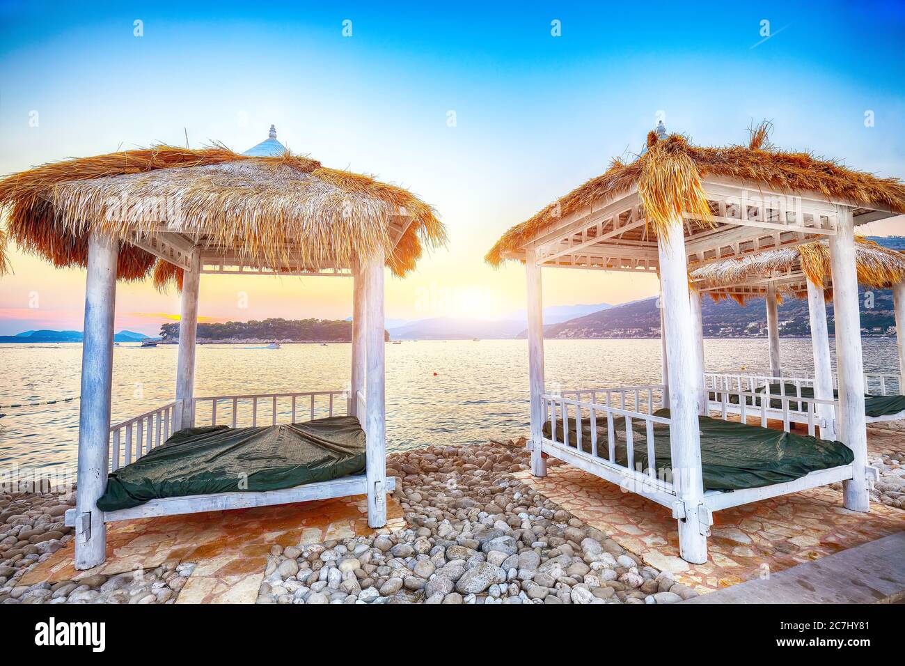 Thatched canopies and awnings on the beach Copacabana at sunset in Dubrovnik. Location:  Dubrovnik, Dalmatia, Croatia, Europe Stock Photo