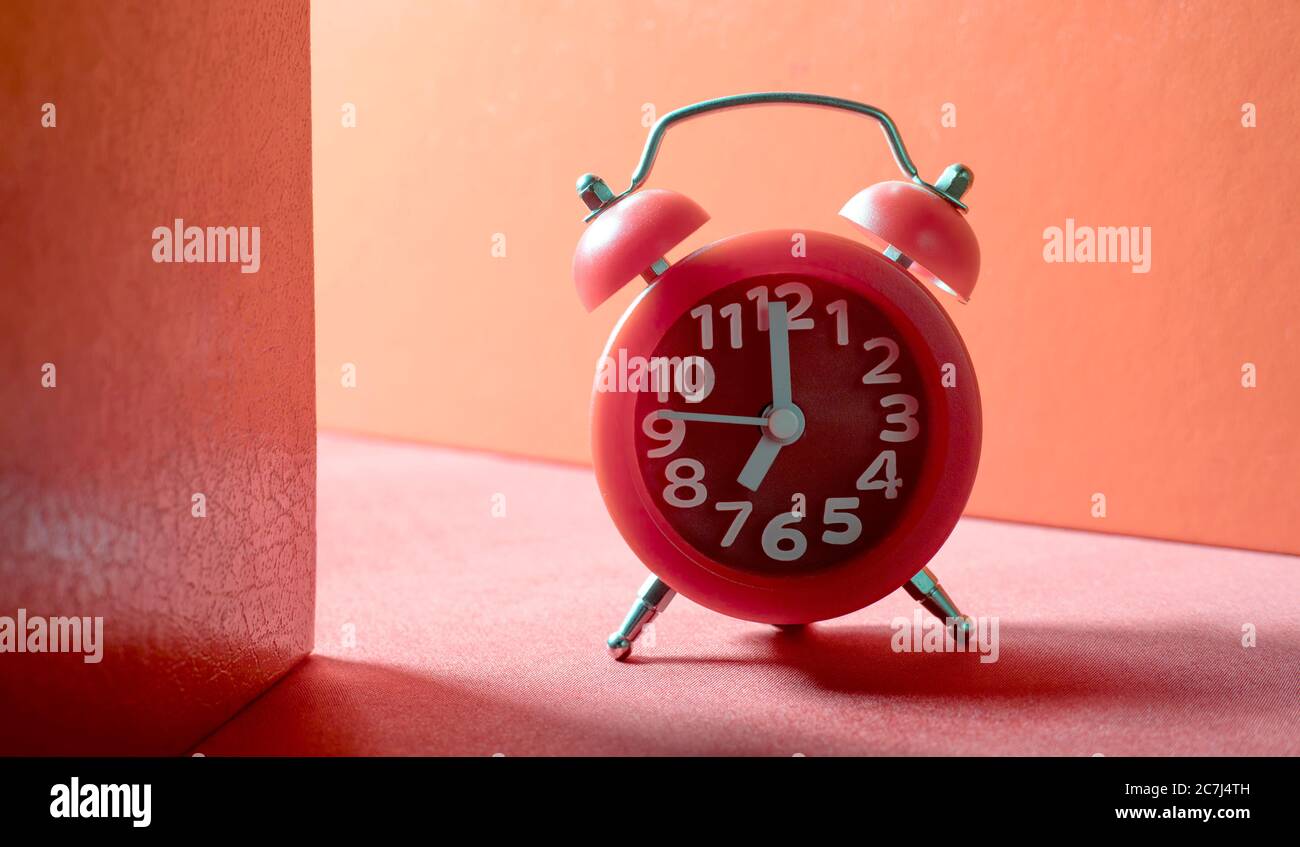 red analog alarm clock on red ground Stock Photo
