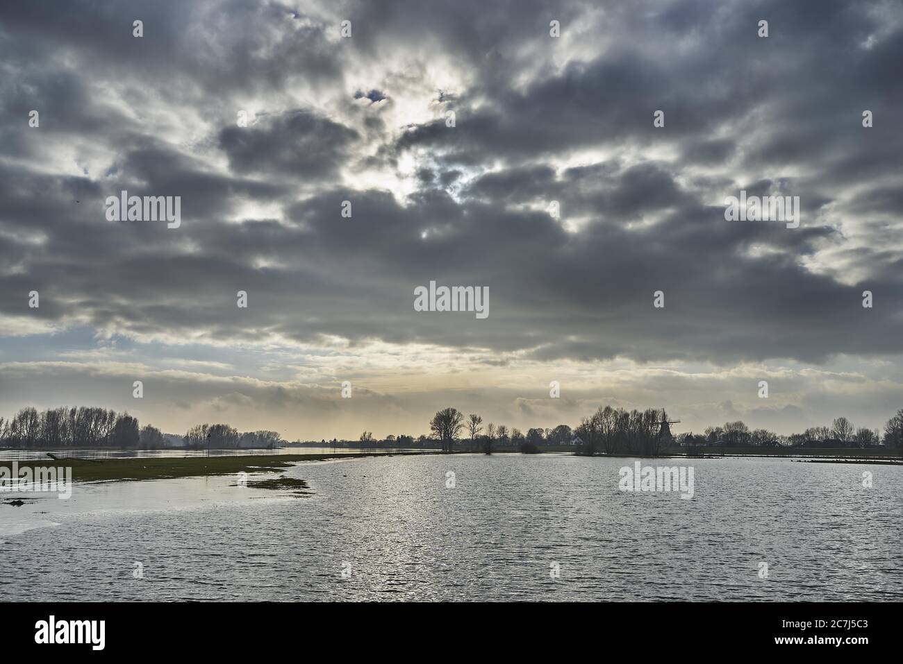 Pure lake under the sky with the sunlight behind the dark clouds Stock