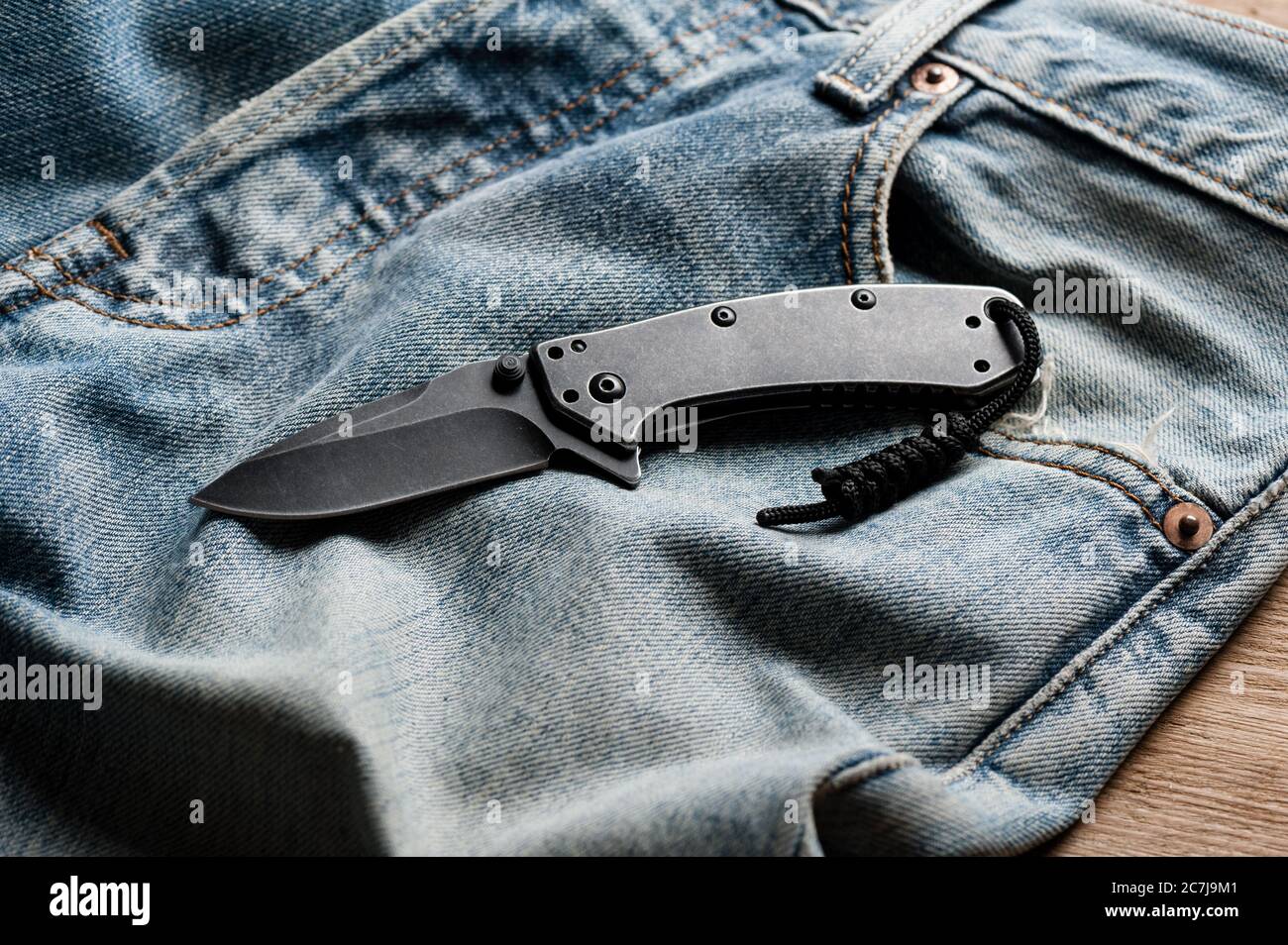 folding knife and jeans. closeup stainless steel pocketknife with