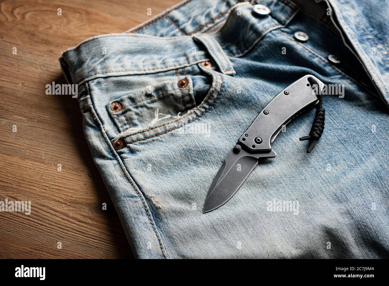 folding knife and jeans. closeup stainless steel pocketknife with