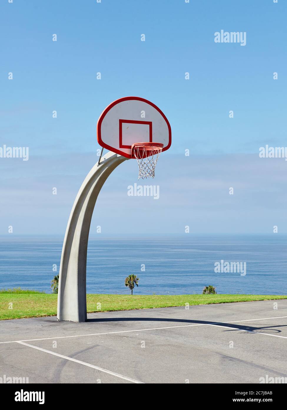 Vertical shot of a basketball hoop near the sea under the beautiful blue sky Stock Photo
