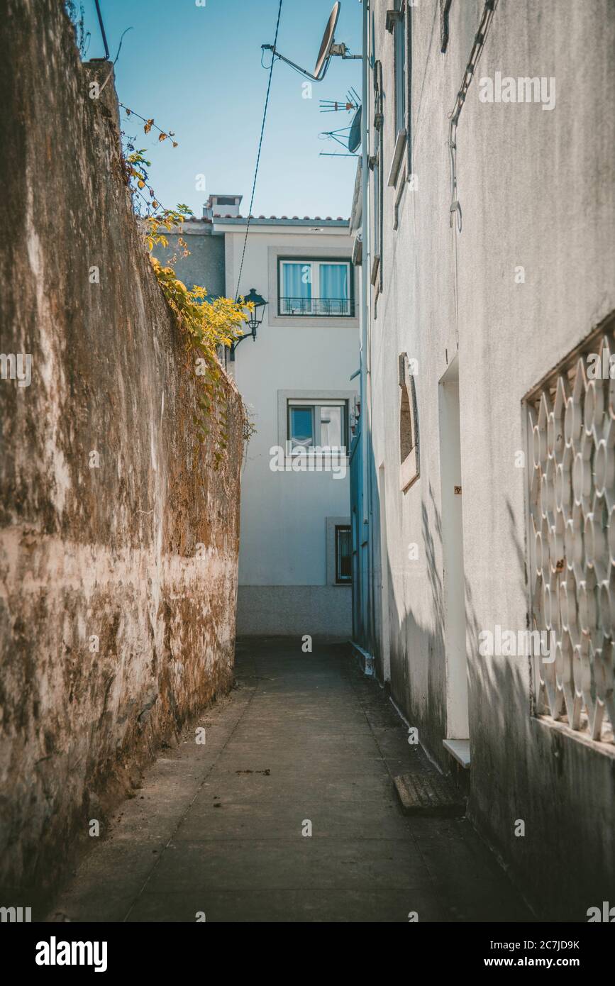 Vertical shot of a narrow pathway in the middle of white buildings ...