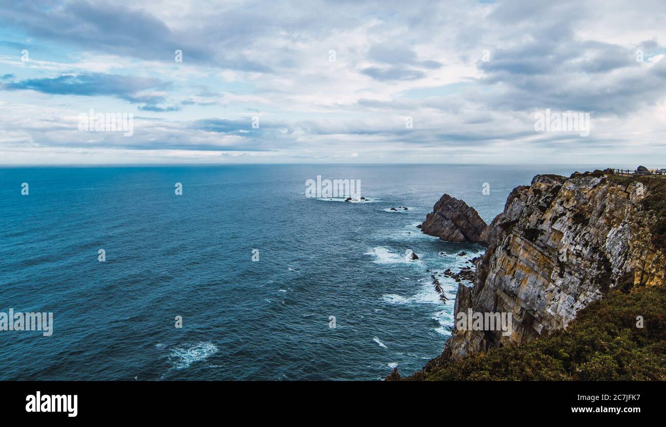 High angle shot of the sea near the mountain under a cloudy sky in Cabo Penas, Asturias, Spain Stock Photo