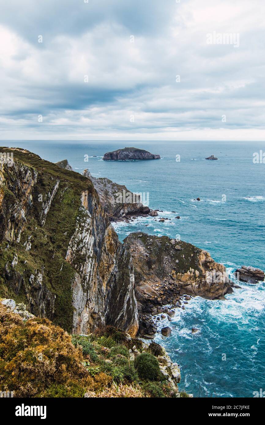 Vertical shot of the mountains near the sea under a cloudy sky in Cabo Penas, Asturias, Spain Stock Photo