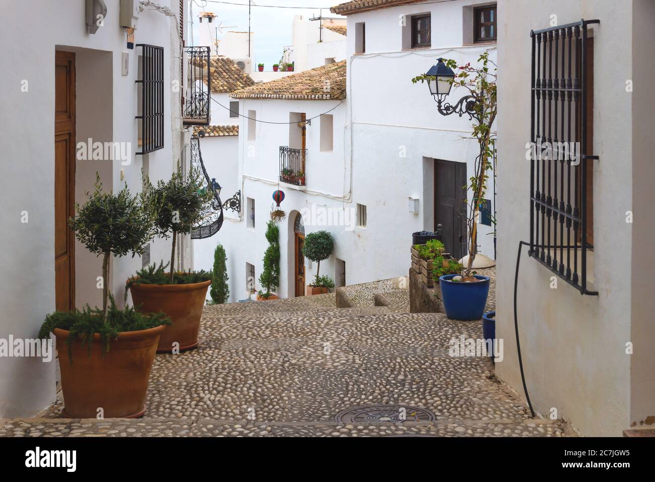 Alley with stairs and flower pots along the white washed houses in the old town of Altea, Costa