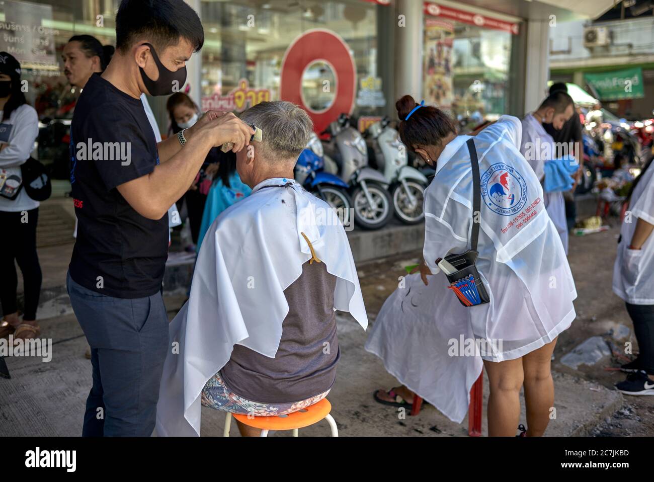 Street haircut. Business promotion of a local Thailand hair salon with people getting a free haircut outside on the pavement sidewalk Stock Photo