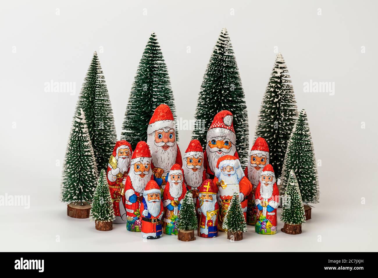 Various chocolate nicholas stand in the midst of miniature Christmas trees, white background, icon image, Christmas time, Stock Photo