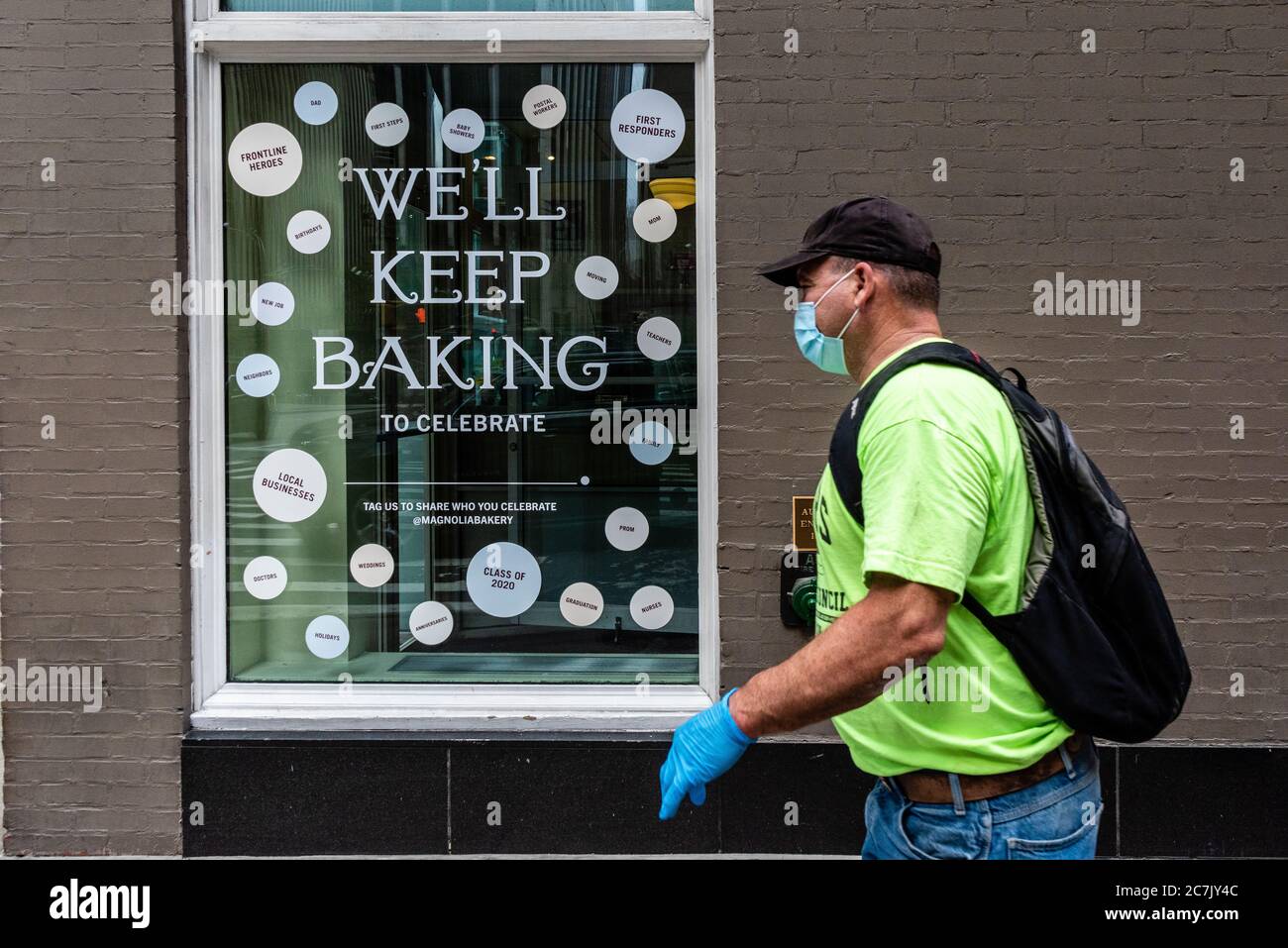 A message in the window of Magnolia Bakery informs customers that they keep on baking despite COVID-19 while a man wearing a face mask walks past the store on July 17, 2020, in New York City. (Photo by Gabriele Holtermann/Sipa USA) Credit: Sipa USA/Alamy Live News Stock Photo