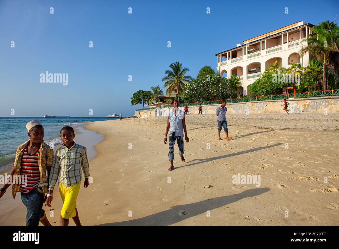 Indian Ocean and Stone Town in Zanzibar, Tansania, East Africa, Citizens walking on the beach Stock Photo
