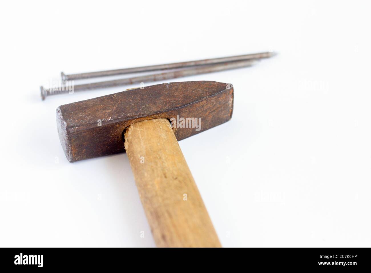 An old hammer and large nails on a white background. Stock Photo
