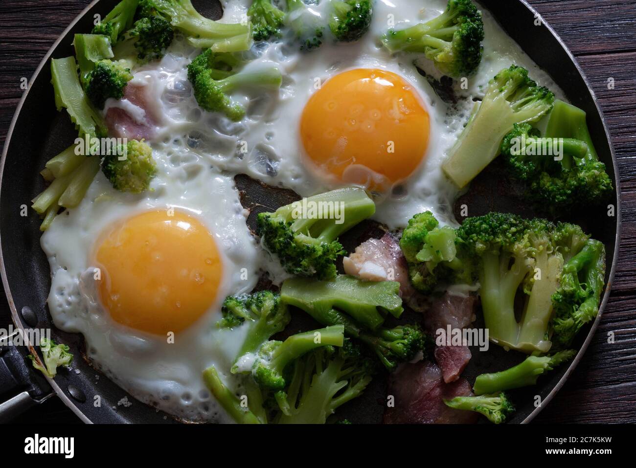 Fried eggs with broccoli and bacon, top view Stock Photo - Alamy