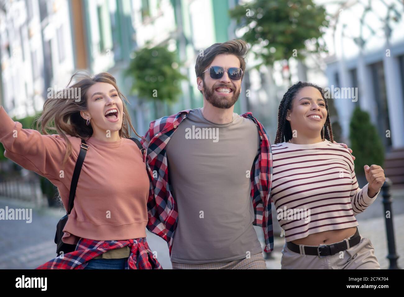 Guy in sun glasses and two pretty girls walking enthusiastic Stock Photo