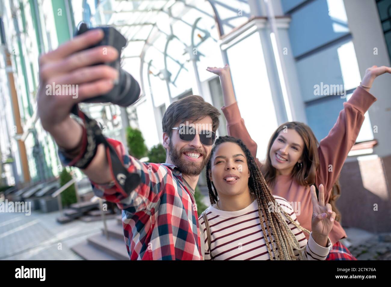Guy taking selfie on camera with two girlfriends. Stock Photo
