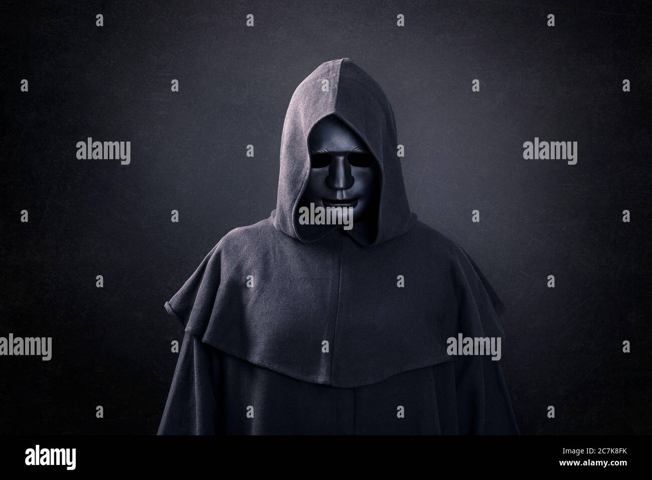 Scary figure with mask in hooded cloak in the dark Stock Photo - Alamy