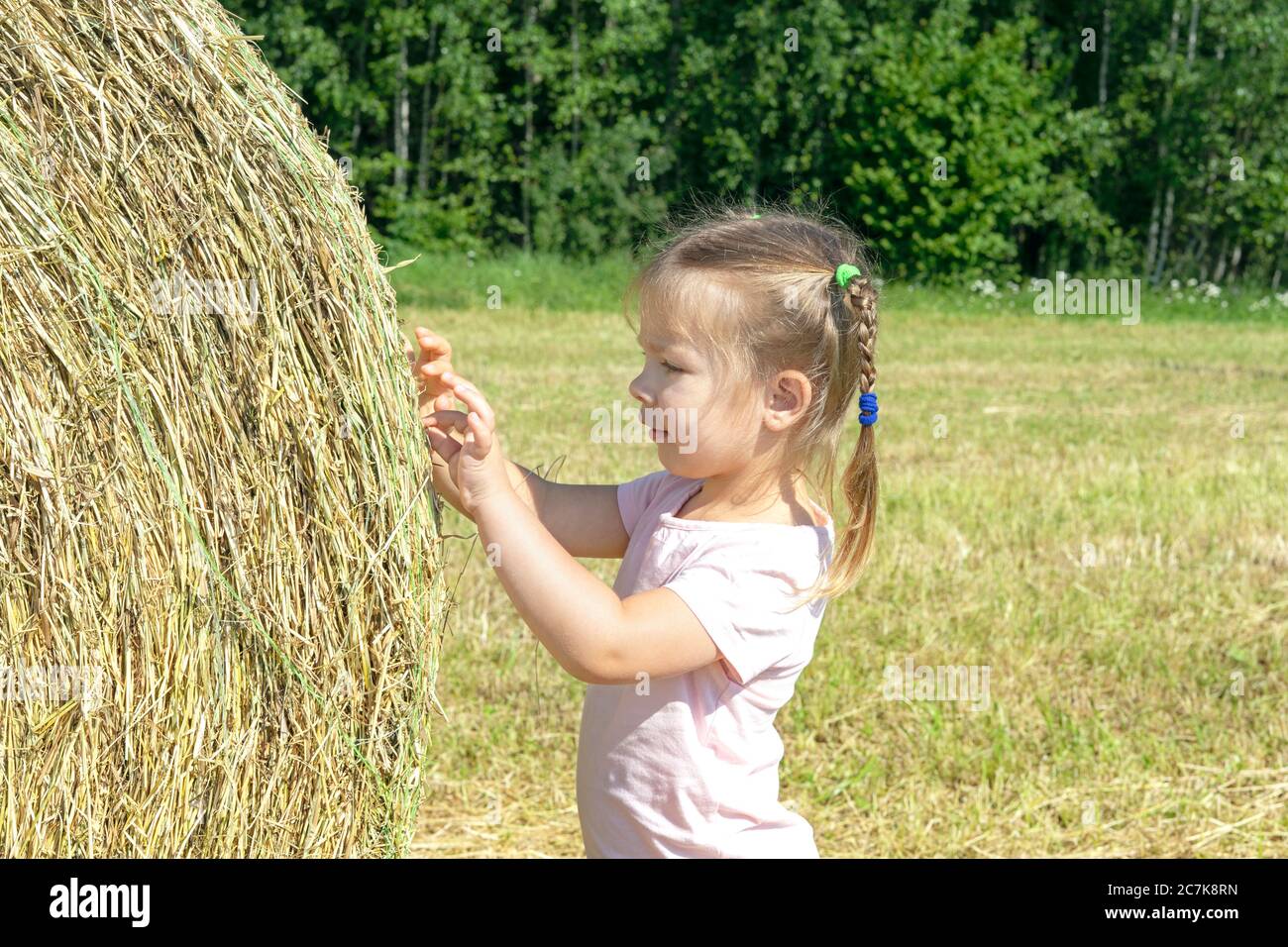 little girl playing by the haystack on a sunny summer day Stock Photo ...