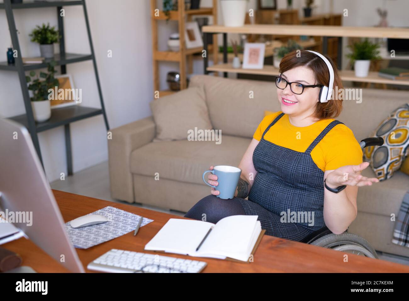 Contemporary young disable female student in headphones having drink