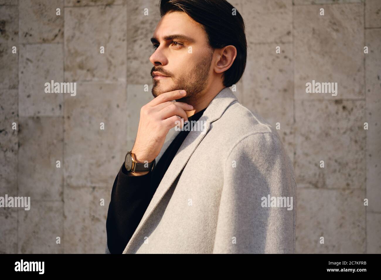 Side view of young handsome man in coat thoughtfully looking away outdoor Stock Photo