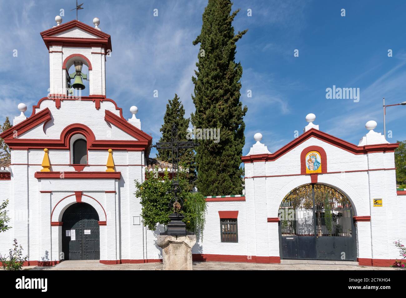 The facade of the Parroquia de San Isidro in Granada with its simple arched entrance, colourful orange obelisks & red framed pediment of its belfry. Stock Photo