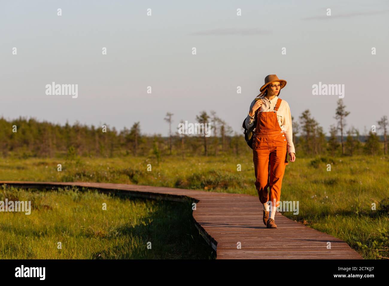 Woman botanist with backpack on ecological hiking trail in summer outdoors. Naturalist exploring wildlife and ecotourism adventure walking on path thr Stock Photo