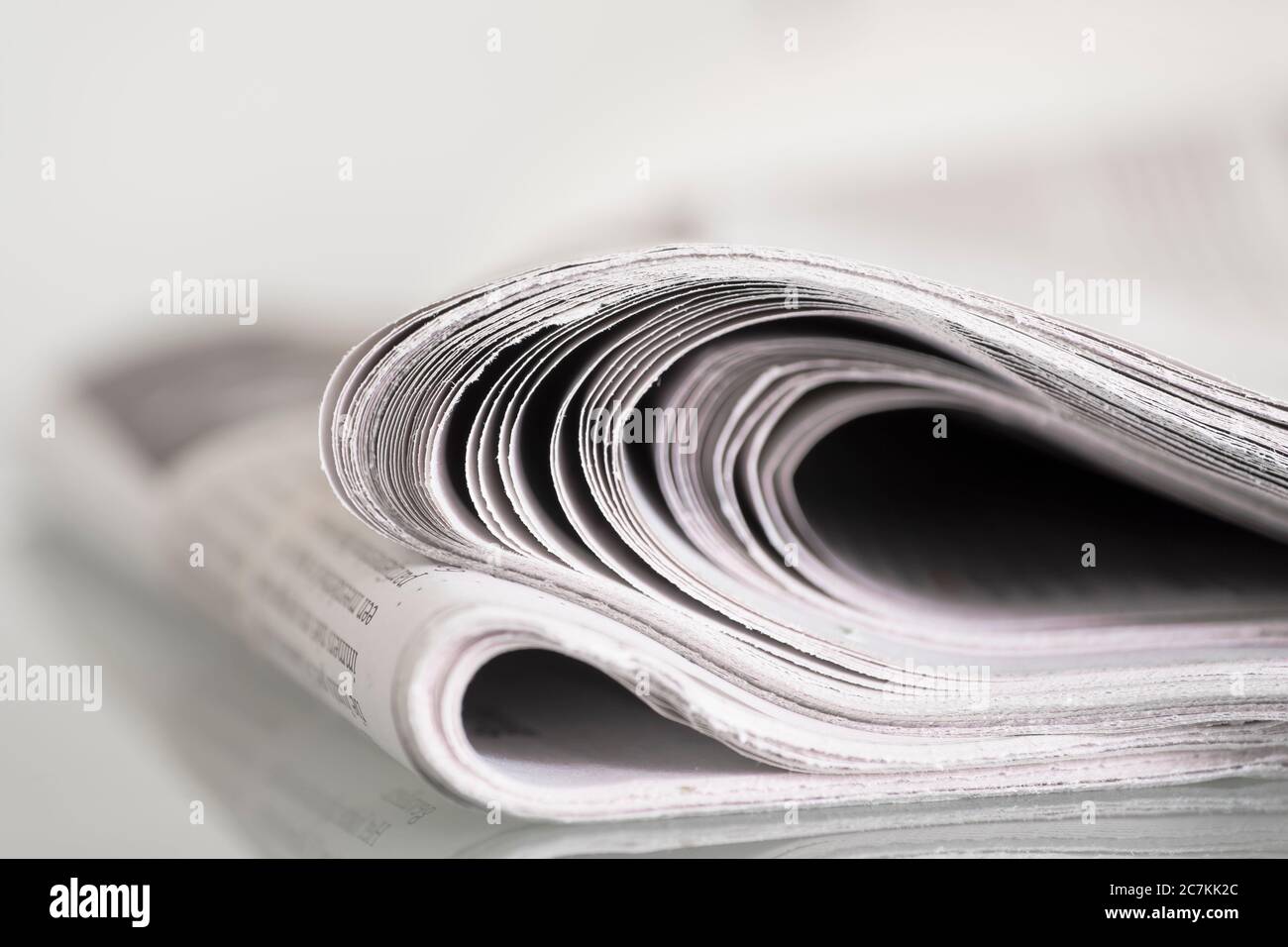 Folded newspaper on a table against plain background with narrow depth of field Stock Photo
