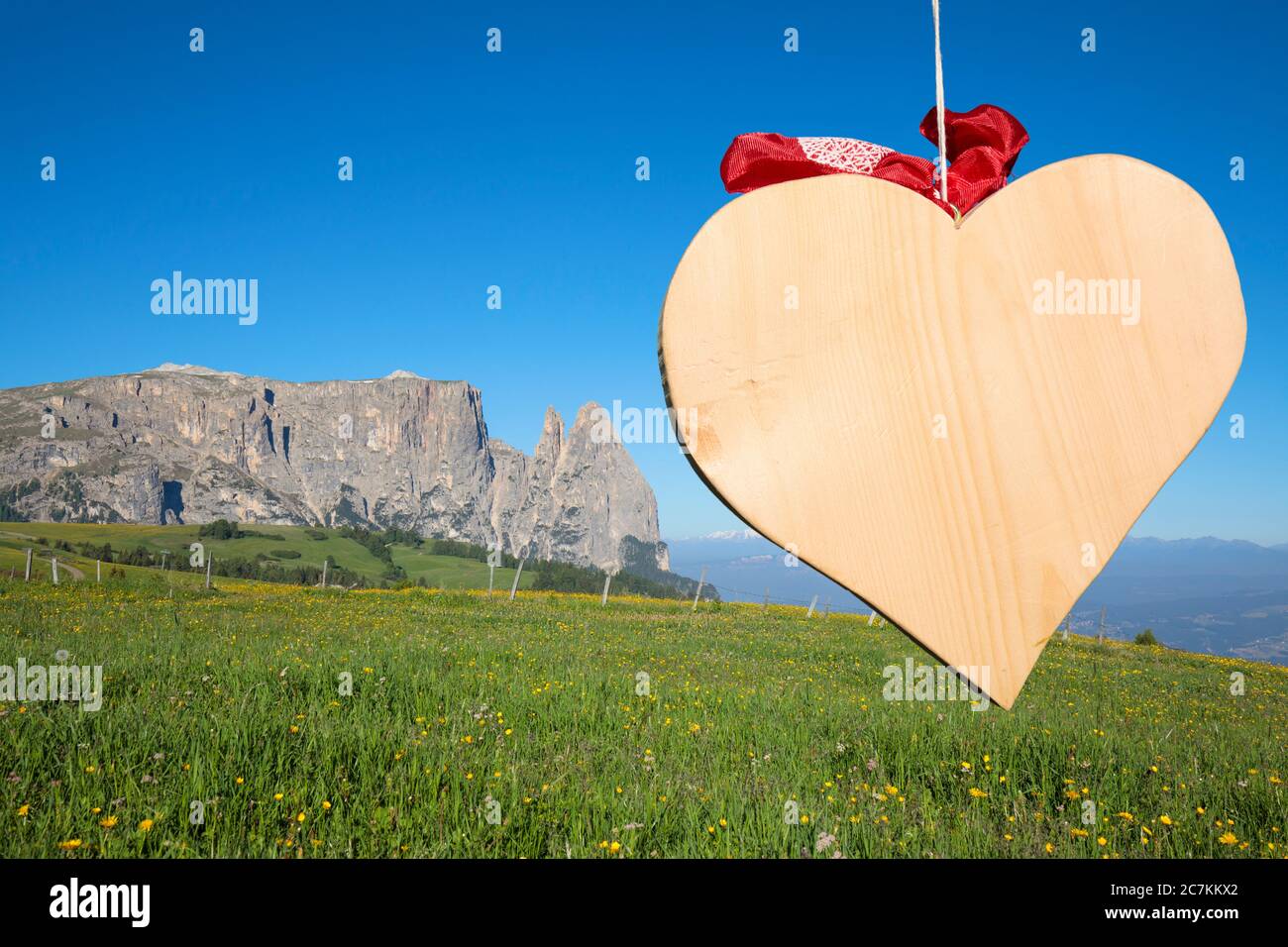 the shape of a wooden heart, in the background the Scilir, Alpe di Siusi (Seiser Alm), Castelrotto (Kastelruth), Dolomites, South Tyrol, Italy Stock Photo