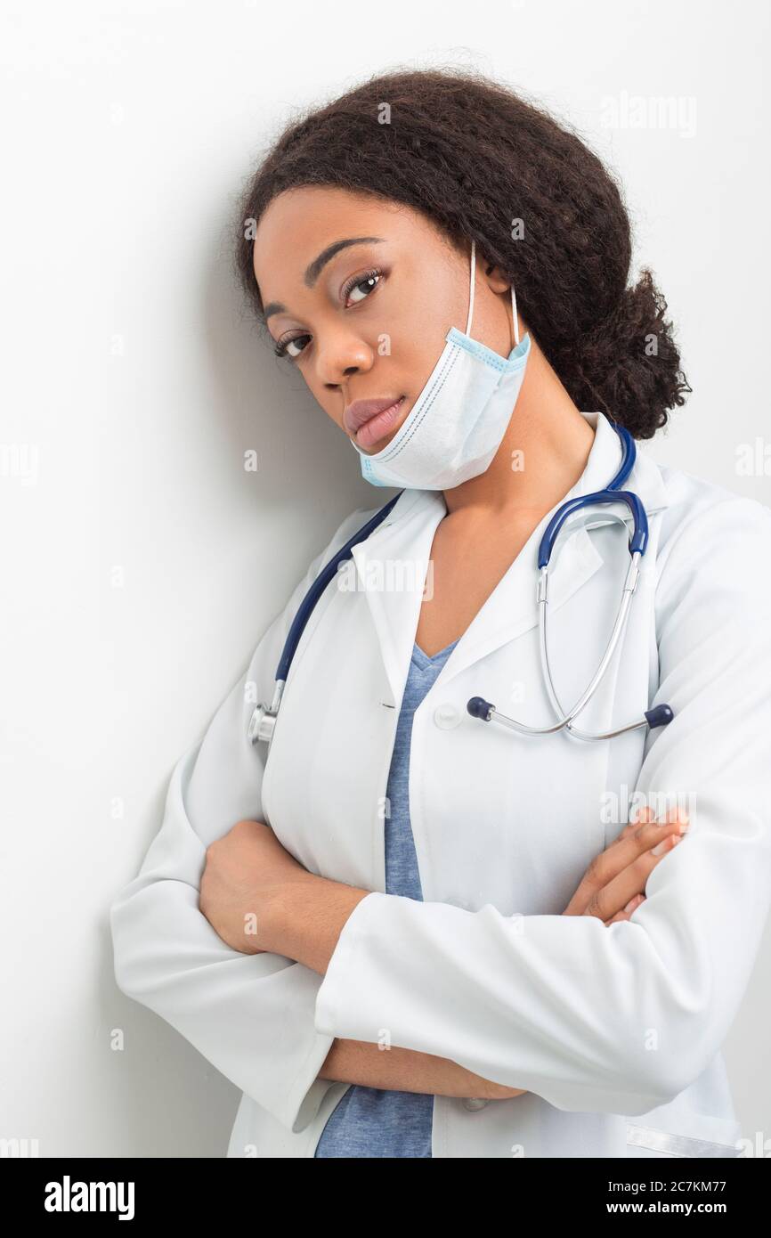 Portrait of an African American nurse in a medical mask and white coat. Tired and sad woman doctor. Stock Photo