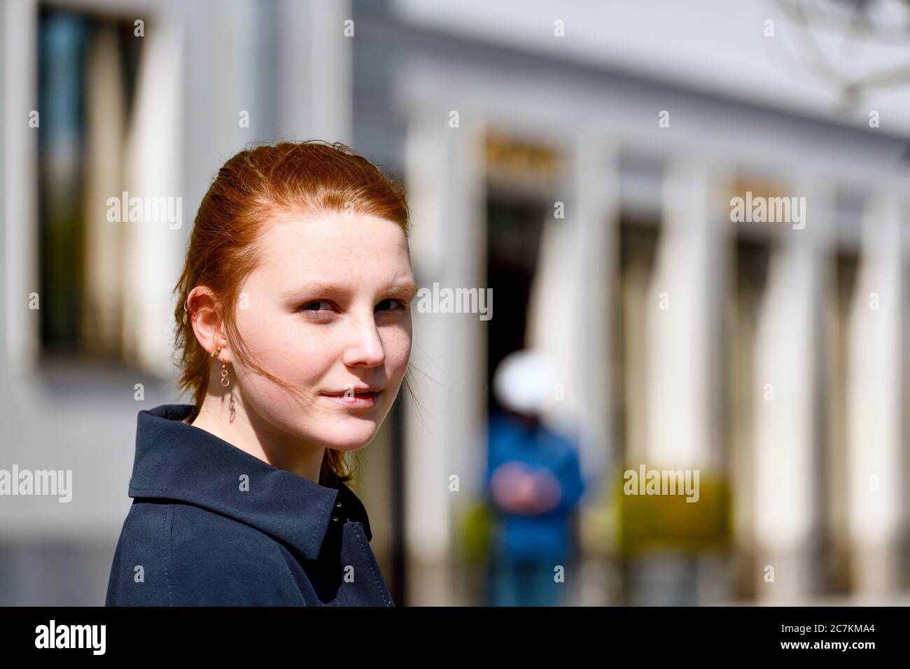 Young girl with reddish hair smiles at camera portrait, outside, side view Stock Photo