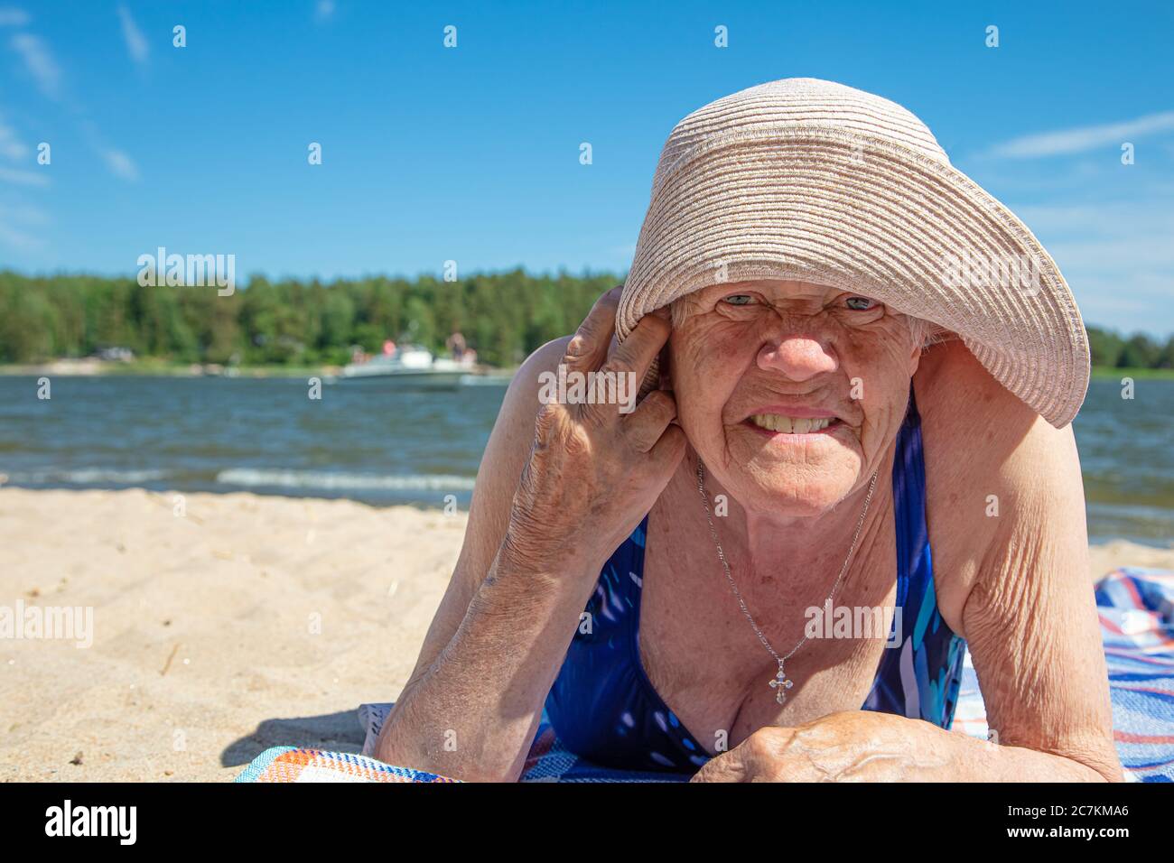 Old woman, in a summer hat and a swimsuit on the beach. Sunny, summer ...