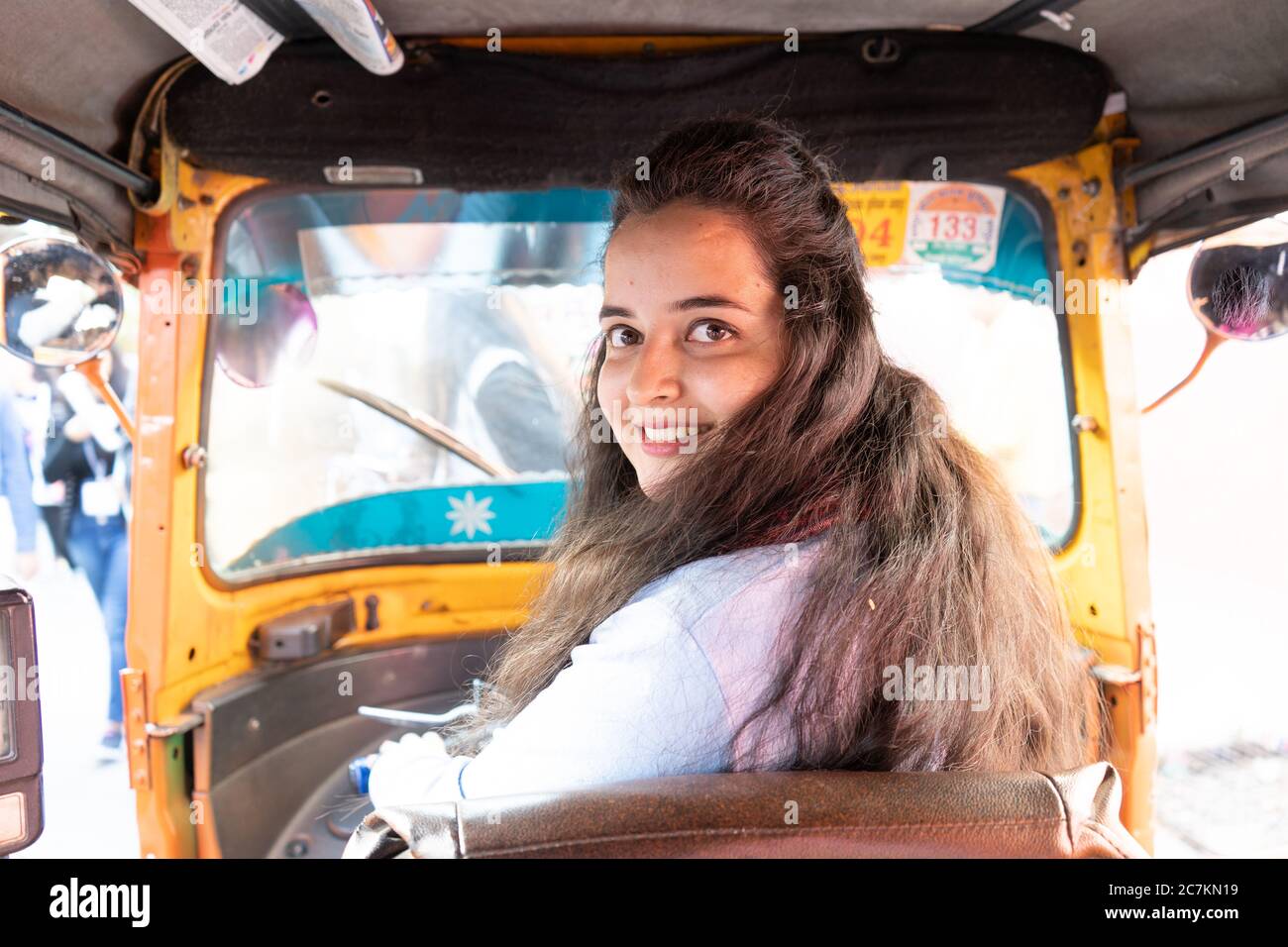 Young indian girl driving an autorickshaw smiling looking back Stock Photo