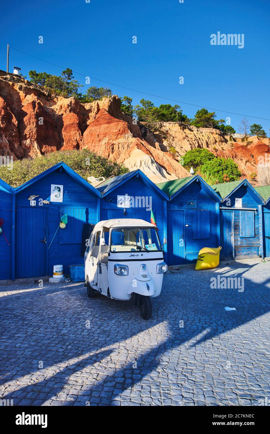 Europe, Portugal, Algarve, Litoral, Barlavento, district Faro, Praia dos Olhos de Agua, blue fishing huts in front of red-brown cliffs with tuktuk, portrait format Stock Photo