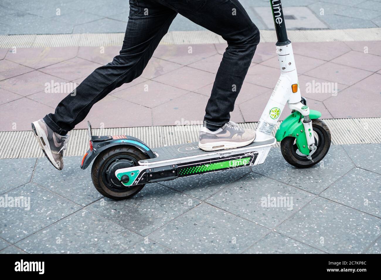 Berlin, Germany - July, 2020: Closeup of a person using a Lime E-scooter or Electric scooter Stock Photo