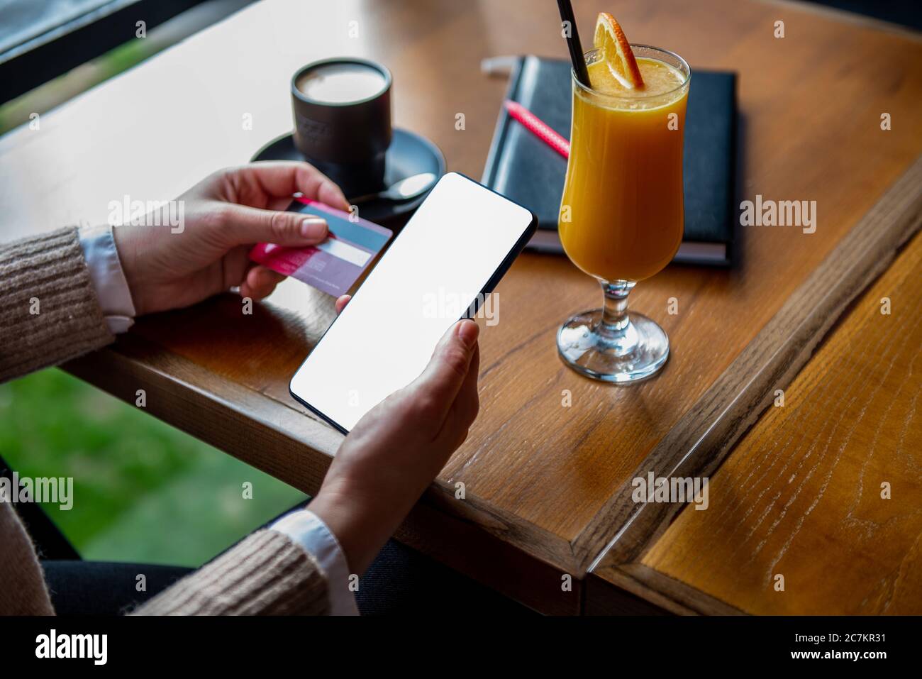 Online shopping , internet concept. Woman using credit card and blank smartphone at cafe. Stock Photo