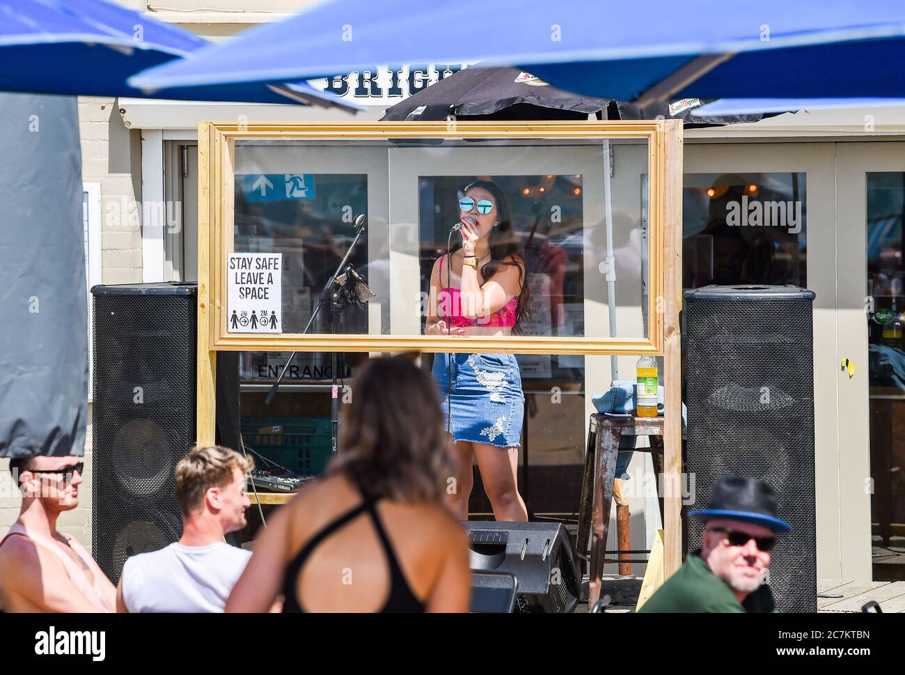Brighton UK 18th July 2020 -  A singer performs at the Brighton Music Hall beach bar behind a screen on a beautiful sunny day on the South Coast with temperatures expected to reach the high 20s in some parts of Britain : Credit Simon Dack / Alamy Live News Stock Photo