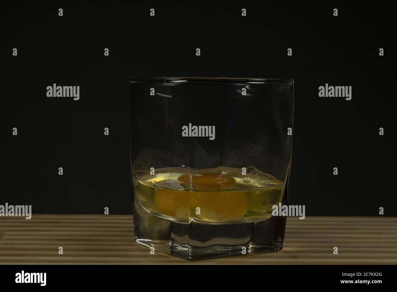 Raw egg in a glass beaker. On a black background Stock Photo