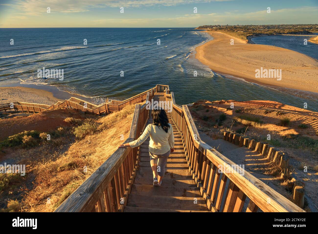 Woman walking down iconic Port Noarlunga boardwalk while watching spectacular sunset view, South Australia Stock Photo