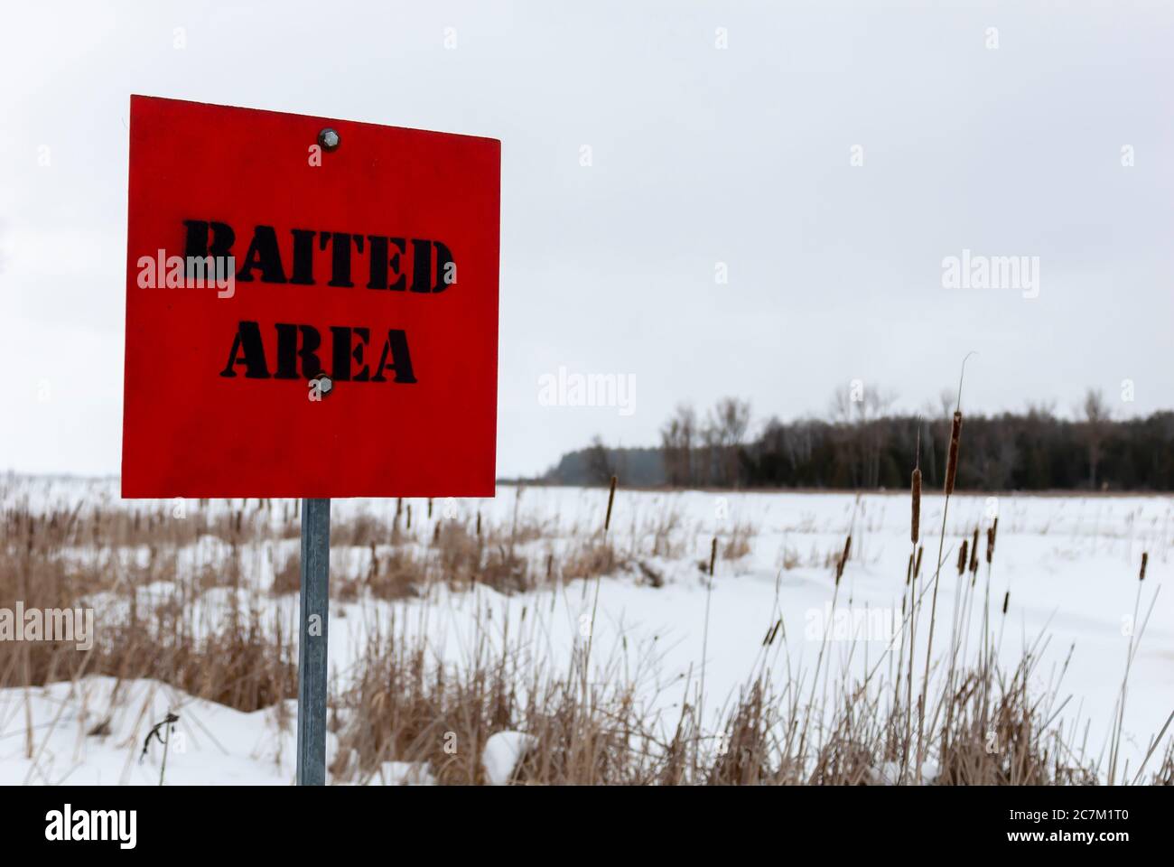 Selective focus shot of a red 'baited area' signage during winter with a blurred background Stock Photo