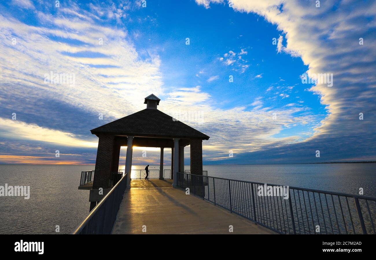 Fontainebleau State Park, Louisiana - February 2018: The silhouette of a visitor inside a gazebo over Lake Pontchartrain in Fontainebleau State Park. Stock Photo